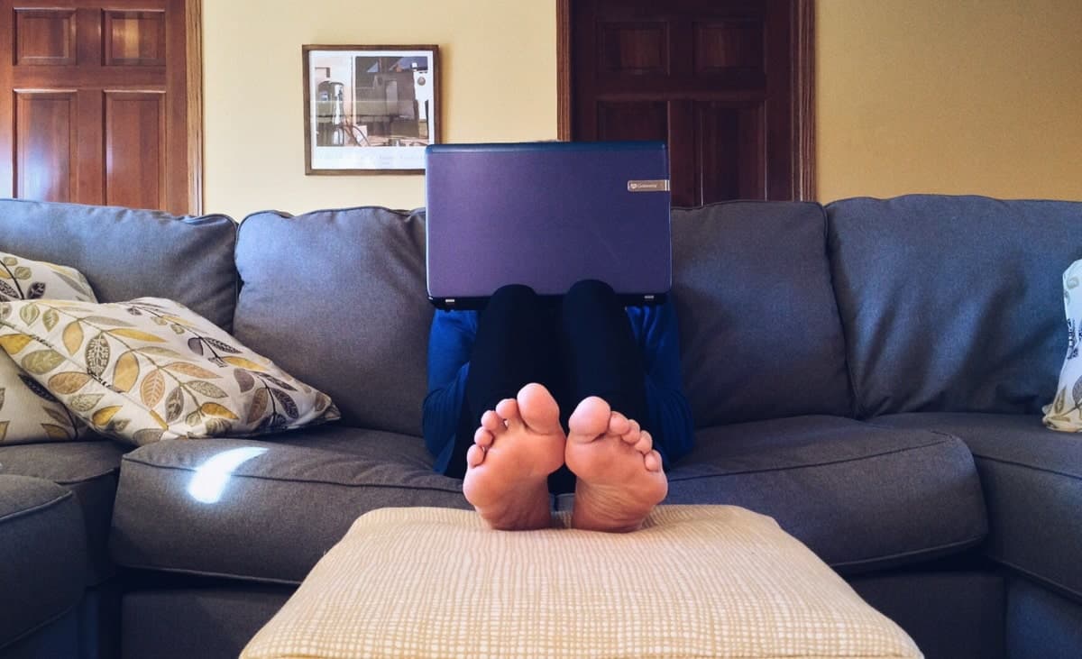 person using a laptop sitting on a sofa